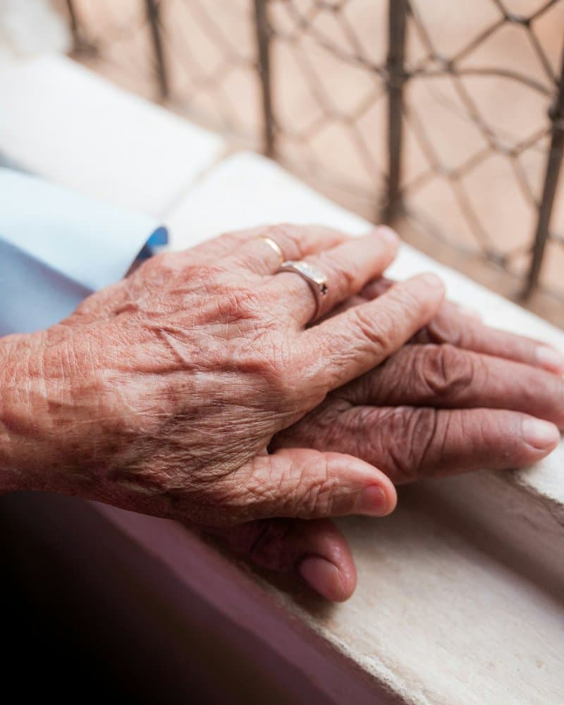 A caregiver engaging gently with an older adult, maintaining eye contact and showing patience
